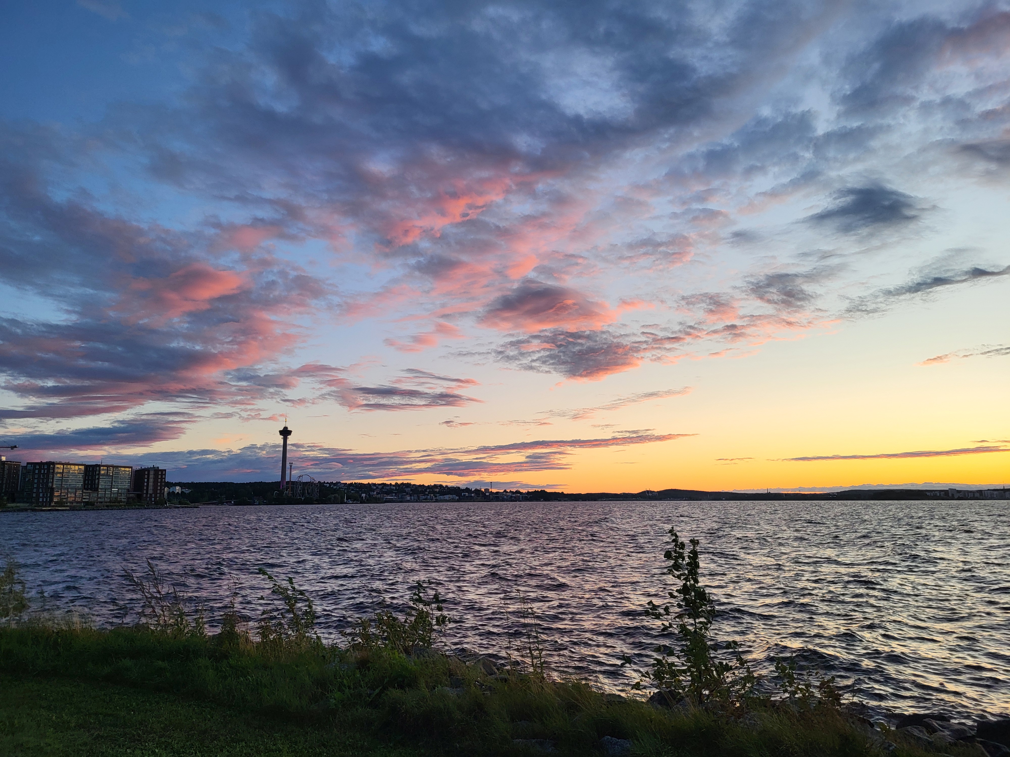 Zonsondergang boven de skyline van Tampere met de Näsinneula-toren, roze-gouden lucht boven de stad